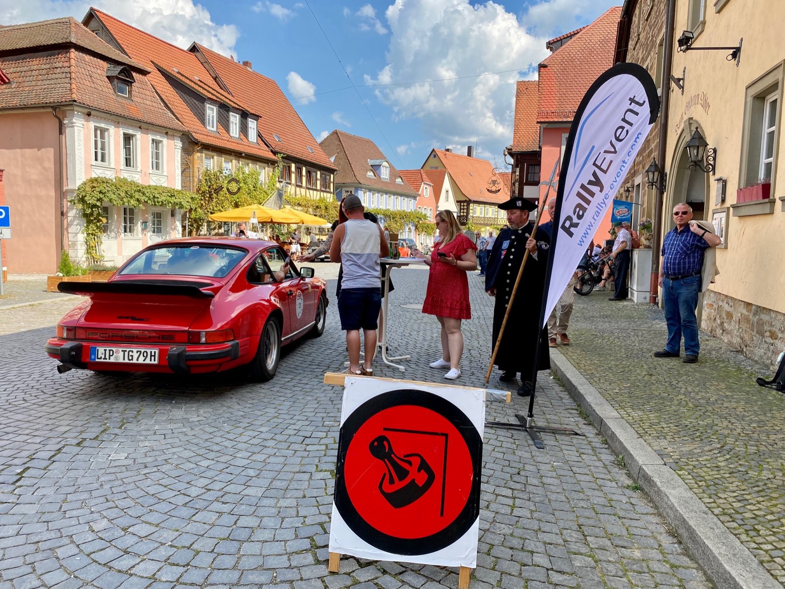 Zeitkontrolle einer Oldtimer-Rallye in einer Altstadt, ein Porsche 911 rollt an den Kontrollposten heran
